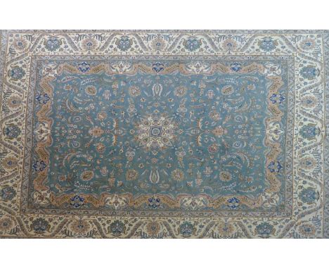 A 20th century Kirman carpet with central floral medallion surrounded by floral motifs and swags, on a turquoise ground, cont