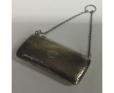 A silver purse of hammered design on suspension chain. Birmingham 1906. By W Turner. Approx. 90 grams. Est. £60 - £80.