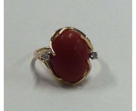 A small diamond and coral three stone cocktail ring in 14 carat gold mount. Approx. 4.4 grams. Est. £100 - £150.