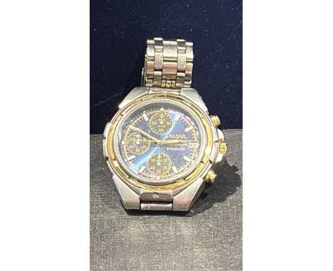 Pulsar chronograph watch features a titanium case with gold-tone accents and a blue dial with three sub-dials and a stainless