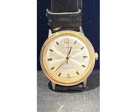 Timex wristwatch with a gold-tone case and black leather strap.