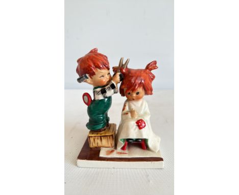 Vintage ceramic figurine depicting a child cutting another's hair, mid-20th century style, colorful glaze, detailed with barb