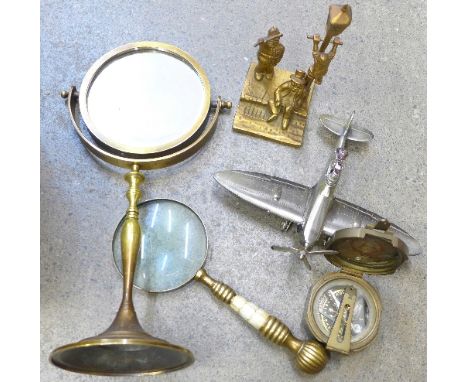 A table lighter in the form of a Spitfire Mk 9, a brass and mother of pearl handle magnifying glass and a brass table mirror,