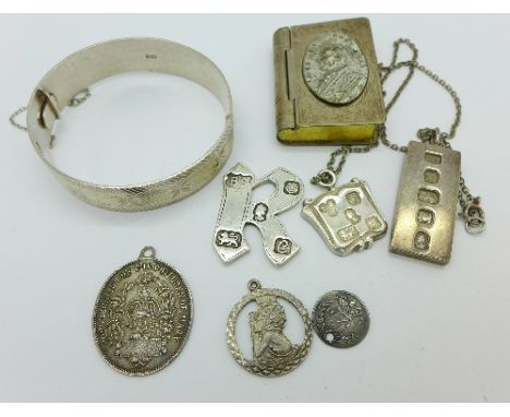 A silver bangle, two silver ingots, three pendants, a silver letter 'R' and a plated box in the form of a book