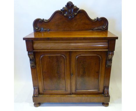 A Victorian Mahogany Chiffonier, the shaped carved back above a concealed frieze drawer, two arched panel doors, raised upon 