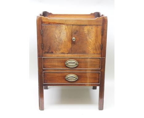 A GEORGIAN MAHOGANY TRAY TOP COMMODE of standard form and design, having twin plain cupboard doors, over faux two drawer fron