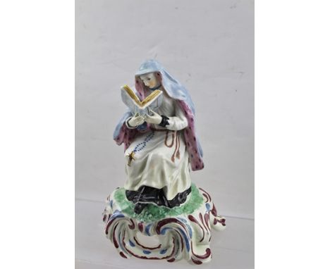 AN 18TH CENTURY PORCELAIN FIGURE, possibly Bow, modelled as a seated Nun reading a religious text, polychrome painted and gil