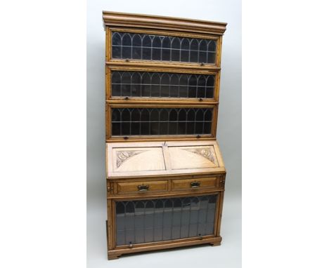 AN EDWARDIAN OAK BUREAU/BOOKCASE with Globe Wernicke design glazed sectional top, the base fitted with writing fall revealing