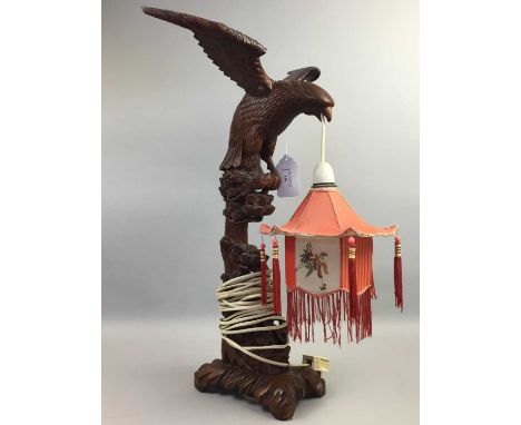 EASTERN CARVED WOOD LAMP,modelled as a hawk atop a pine tree, holding a lantern in its beak, 60cm high