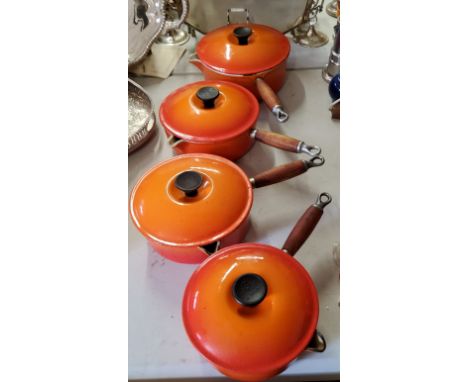 Le Creuset a set of four graduated cast iron, orange enamel saucepans &amp; covers 