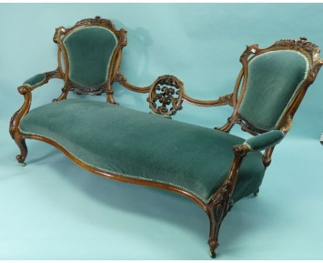 An early Victorian walnut framed Sofa, with two rounded ends and serpentine seat, the low back with foliate carved and pierce