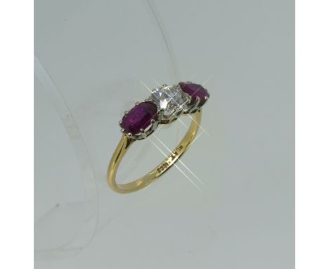 A three stone ruby and diamond Ring, the central brilliant cut diamond, c. 0.6ct, with an oval set ruby on either side, mount