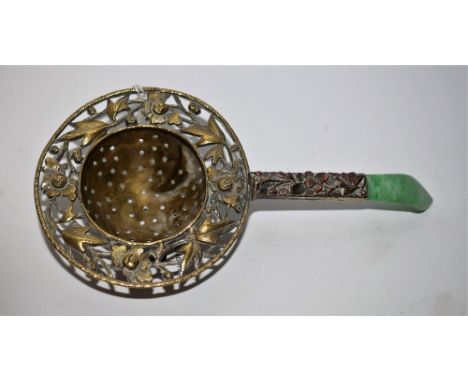A Chinese white metal tea strainer, pierced with leaves and flower heads, the handle with Jade terminal, 15cm long, early 20t
