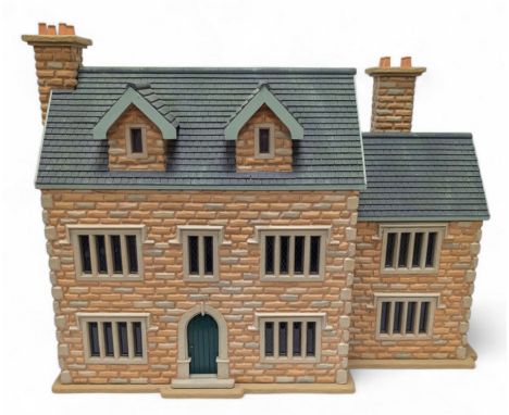 1:24 scale stone effect three-storey cottage dolls house, with green arched door and lattice effect windows, decorated to the