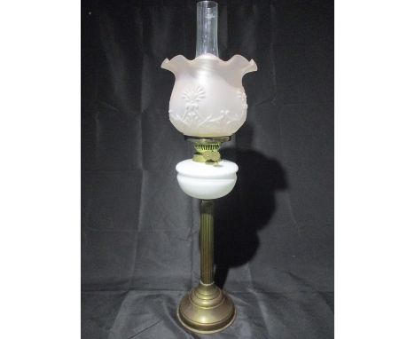 A brass oil lamp with white reservoir, glass frosted shade etched with floral pattern and funnel