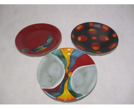 Three Poole Pottery plates with adhesive hangers to reverse