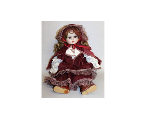 A GOOD GERMAN BISQUE HEADED DOLL wearing a velvet cloak.