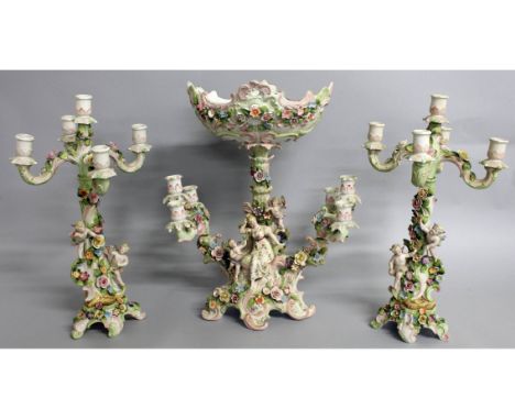A CONTINENTAL PORCELAIN THREE PIECE GARNITURE comprising centre comport, flanked by five light candelabra encrusted with flow