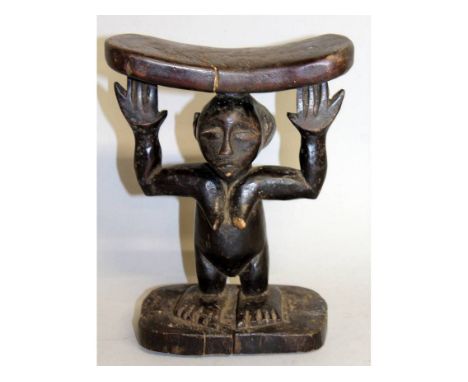 A CARVED TRIBAL STOOL as a woman holding aloft a plank. 10ins high.
