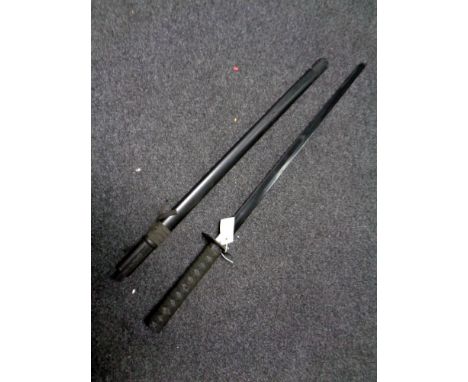 A reproduction samurai sword in scabbard on display stand   