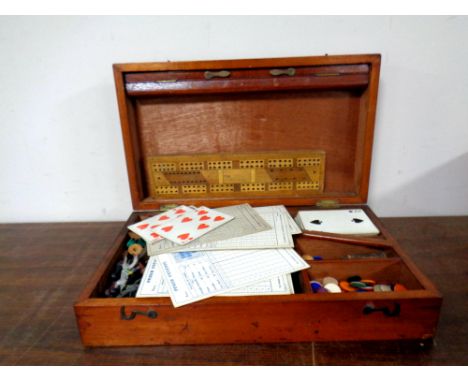 An Edwardian mahogany games box containing drafts, counters, cards, wooden cribbage board  