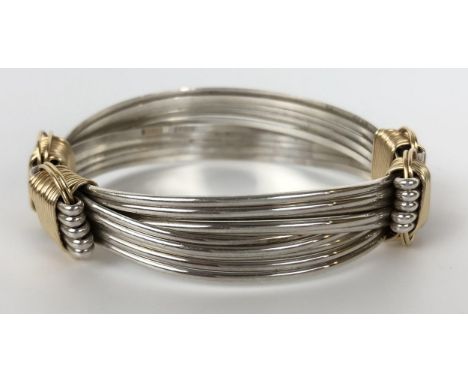 A silver coloured metal and yellow coloured metal adjustable bangle 