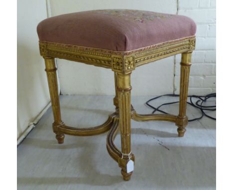 A late 19thC Louis XVI style gilt gesso framed square stool with a tapestry upholstered seat, raised on turned, tapered, flut