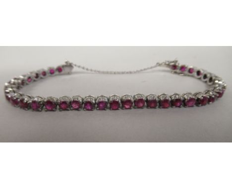 A white metal claw set ruby bracelet 