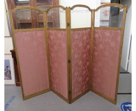 A late 19thC Continental four fold gilded hardwood dressing room screen, the top panels set with clear bevelled glass, over t