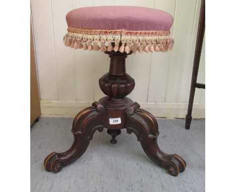 A late Victorian carved walnut revolving music stool with a tapestry upholstered seat, raised on cabriole tripod base 