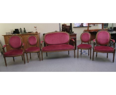 A late 19thC Continental carved giltwood, showwood framed salon suite, each crest with a ribbon tied bow motif, upholstered i