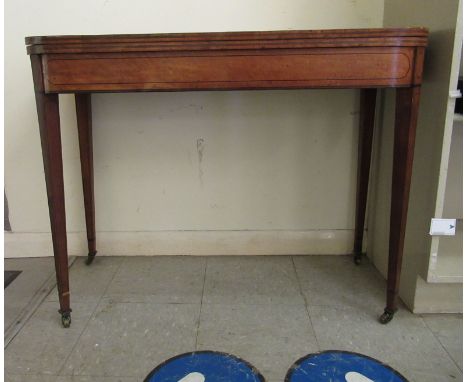 A Regency satinwood and ebony inlaid mahogany card table, the foldover top enclosing a baise lined interior, raised on tapere