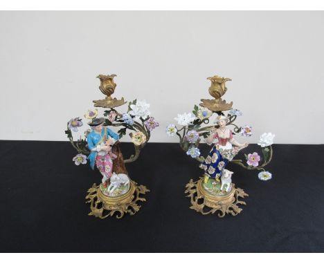 A pair of ormolu candlestick depicting shepherd and shepherdess and decorated with porcelain flower meads, 27cm tall