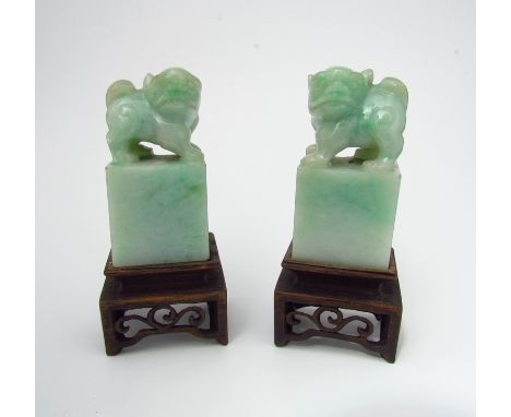A pair of carved jade Dogs of Fo seals on carved wooden stands 