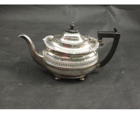 A silver teapot with ebony finial and handle fluted band to body, raised on four feet, Chester 1913