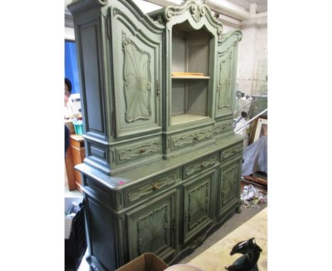 A French green painted cabinet having a double arched top over a shelf, flanked by two doors, above three in-line drawers, th