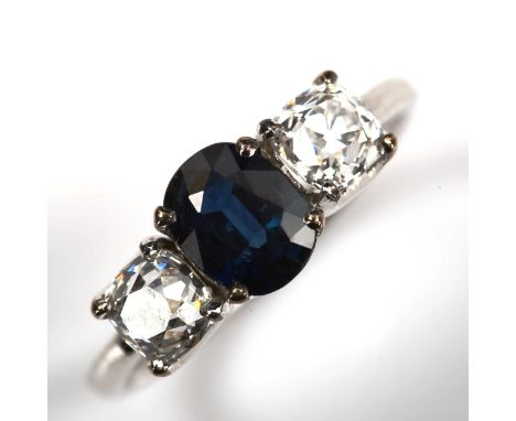 A three stone sapphire and diamond ring, unmarked white metal settings with oval mixed-cut sapphire and old mine-cut diamonds