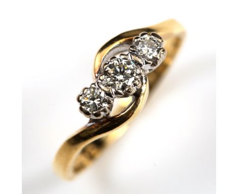 An 18ct gold three stone diamond cross over ring, set with modern round brilliant-cut diamonds, total diamond content approx 