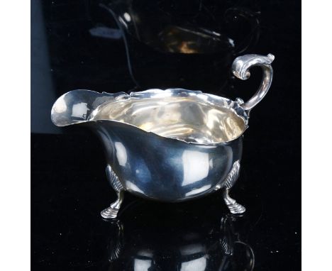 An Edwardian Scottish silver sauce boat, with scalloped rim, scrolled acanthus leaf C-shaped handle and hoof feet, by Hamilto