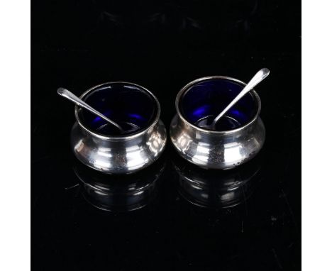 A pair of George V silver salt cellars and spoons, with blue glass liners, by Deakin & Francis, hallmarks Birmingham 1911, di