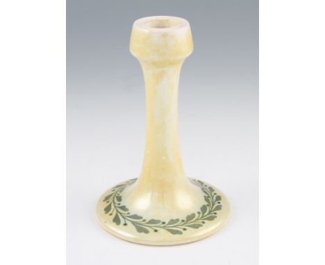 A Ruskin pottery candlestick with yellow glazed body with a green laurel leaf repeat design to the foot, shape 106, base stam