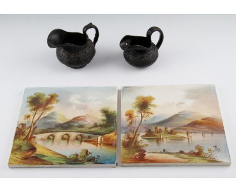 Two early 20th Century hand painted ceramic tiles, both having hand painted landscape scenes, one having a lake the other hav