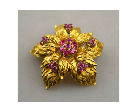 A retro style yellow metal chrysanthemum brooch with textured leaves having central set ruby cluster with five ruby trefoils 