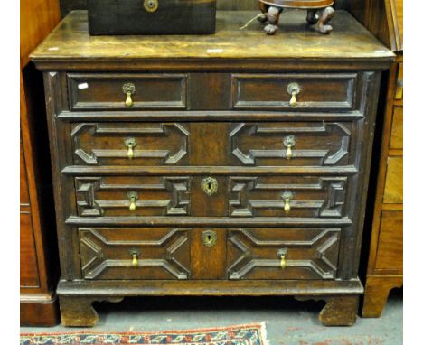 A 17th century oak chest of four long graduated drawers, having applied geometric mouldings and brass drop pulls, raised on s