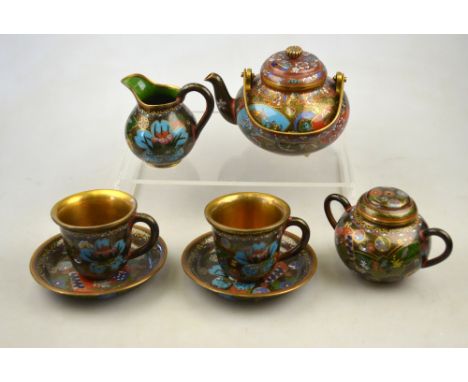 A Japanese cloisonne tea set for two decorated with shaped panels of water lilies and wisteria, comprising a teapot with swin