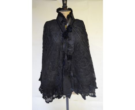 A Victorian black silk and velvet cape elaborately embellished with tape-work, to/w a black silk velvet cloak with cream lini