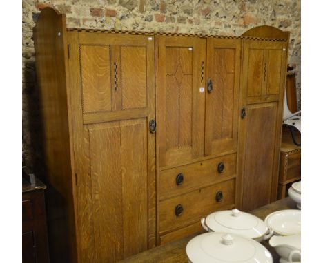 A feather-banded light oak compactum/wardrobe having a three-quarter galleried top over a pair of cupboard doors and three dr