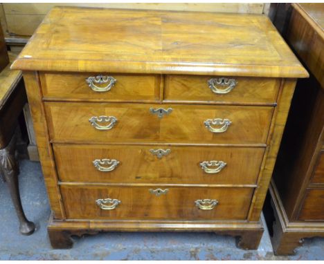 An 18th century feather-banded walnut chest of two short over three long graduated drawers with fret-cut brass pulls, raised 