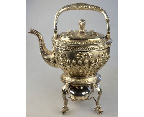 An Indian white metal kettle on stand richly embossed and chased with processional figures bearing effigies of Shiva, within 