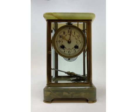 A mantel clock, the porcelain dial with Arabic numerals, to twin train movement, striking on a gong, in an onyx and four glas